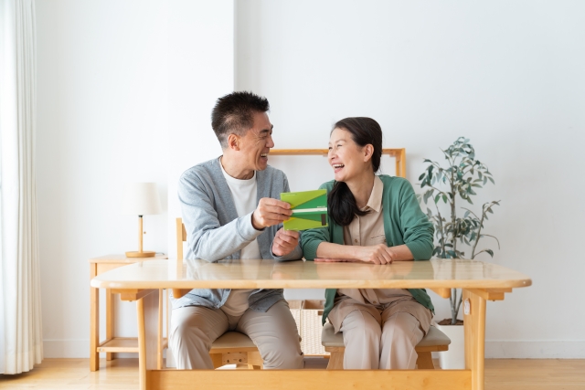 通帳を見ながら笑う夫婦
